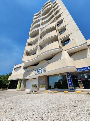 Ein mehrstöckiges Hotel mit modernem Design, mit einem gut sichtbaren 'Oasis'-Schild, einem Eingangsbereich auf Straßenniveau und einer erkennbaren Schaufensterfront.
