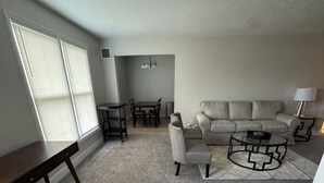 Una sala de estar con un sofá, una mesa de centro y un comedor con mesa y sillas.