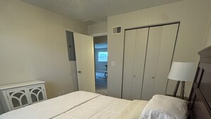 Una habitación de hotel con una cama grande, una mesita de noche, una lámpara y un armario.