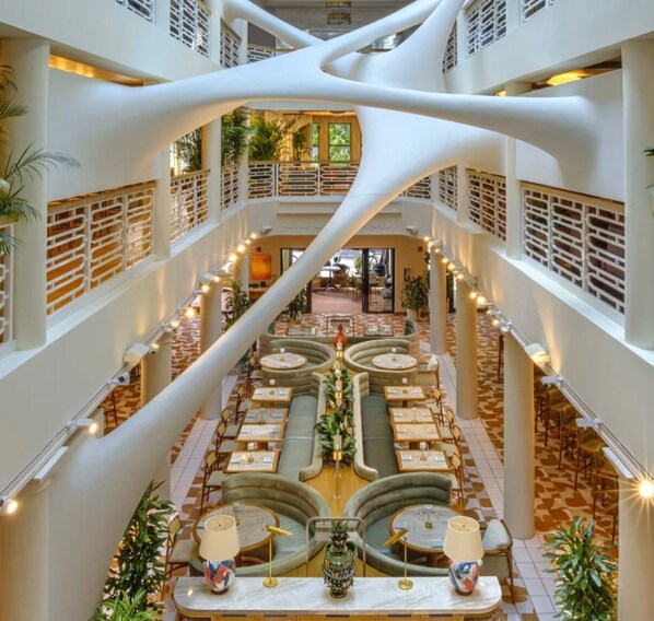 Un vestíbulo de hotel de varios niveles con una zona de estar central, varios pisos y un diseño arquitectónico distintivo.