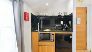 A compact kitchen with a microwave, toaster, and coffee maker on a glass countertop. - Central London 1-Bed Flat – Hyde Park & Paddington Area (London)