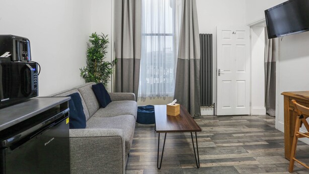 A modern living room with a sofa, a coffee machine, a television, a wooden table, and a plant. - Central London 1-Bed Flat – Hyde Park & Paddington Area (London)