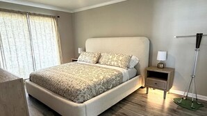 Un dormitorio con cama, mesita de noche, lámpara y ventilador de techo.