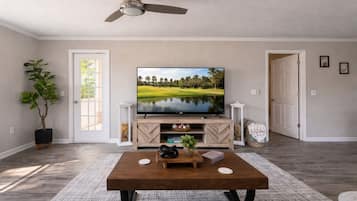 A living room with a television, a coffee table, a potted plant, and a door.