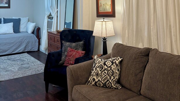Ein Zimmer mit einer Chandelüster, einem Sofa, einem Sessel, einem Bett und einer Lampe.
