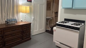 Eine Küche mit Herd, einem Holzschrank, einem Wasserspender und einer Tür zu einem Abstellraum.
