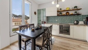 Cozinha moderna com área de jantar, vista através de uma grande janela e painel de azulejos.