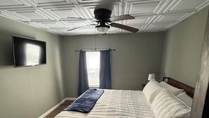 A bedroom with a bed, a ceiling fan, a window with curtains, and a mounted TV. - Quiet Place Close to Utica, Cooperstown, Thruway, and NYS Canal Trail (Mohawk)
