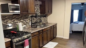 A kitchen with dark wooden cabinets, a stainless steel stove, a microwave, and a patterned backsplash. - Quiet Place Close to Utica, Cooperstown, Thruway, and NYS Canal Trail (Mohawk)