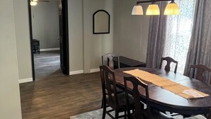 A dining area with a wooden table, chairs, a patterned rug, and a ceiling with a grid design. - Quiet Place Close to Utica, Cooperstown, Thruway, and NYS Canal Trail (Mohawk)
