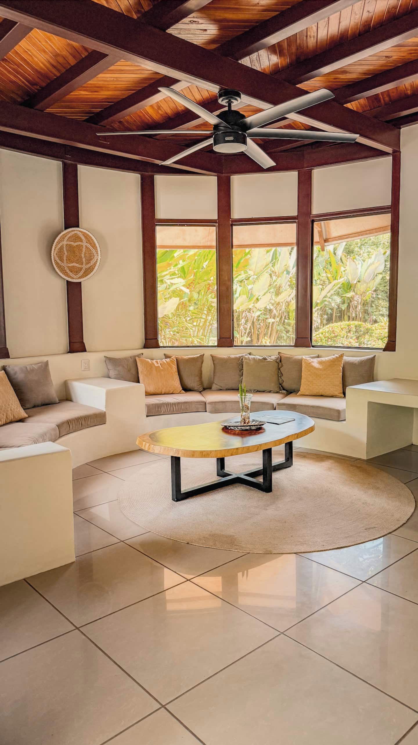 Uma sala de estar moderna com ventilador de teto, mesa de centro redonda e um conjunto de sofá.