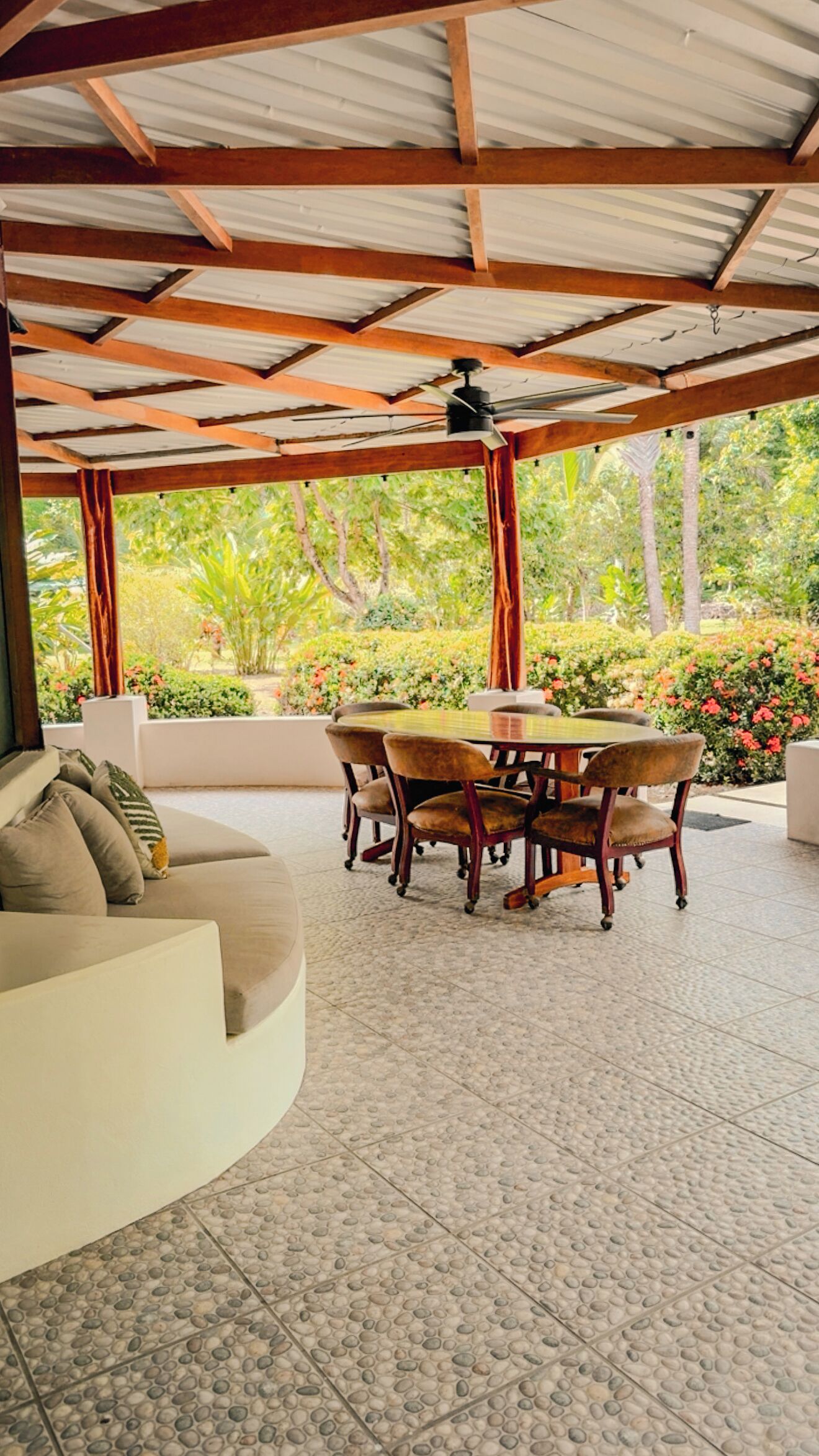 Un espace extérieur abrité, aménagé avec une table et des chaises, un canapé et un ventilateur de plafond.