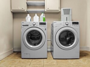 Two front-loading washing machines in a laundry room with cabinets above and a dryer on the right. - The Pond House: Cozy Home with a View, Swimming Pond, and Hot Tub, Pet-Friendly! (Margaretville)