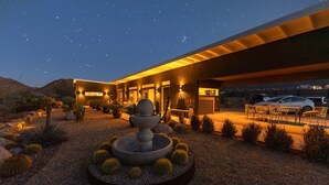Een modern gebouw met een ronde fontein in het midden, omringd door cactussen en woestijnplanten.