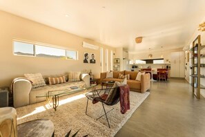 A spacious living area with a sofa, coffee table, and dining area. - Desert Dawn | Spa | Fire Pit | 5 Minutes To Park (Joshua Tree)