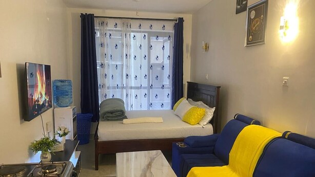 A compact living space with a bed, sofa, and a small kitchen area.