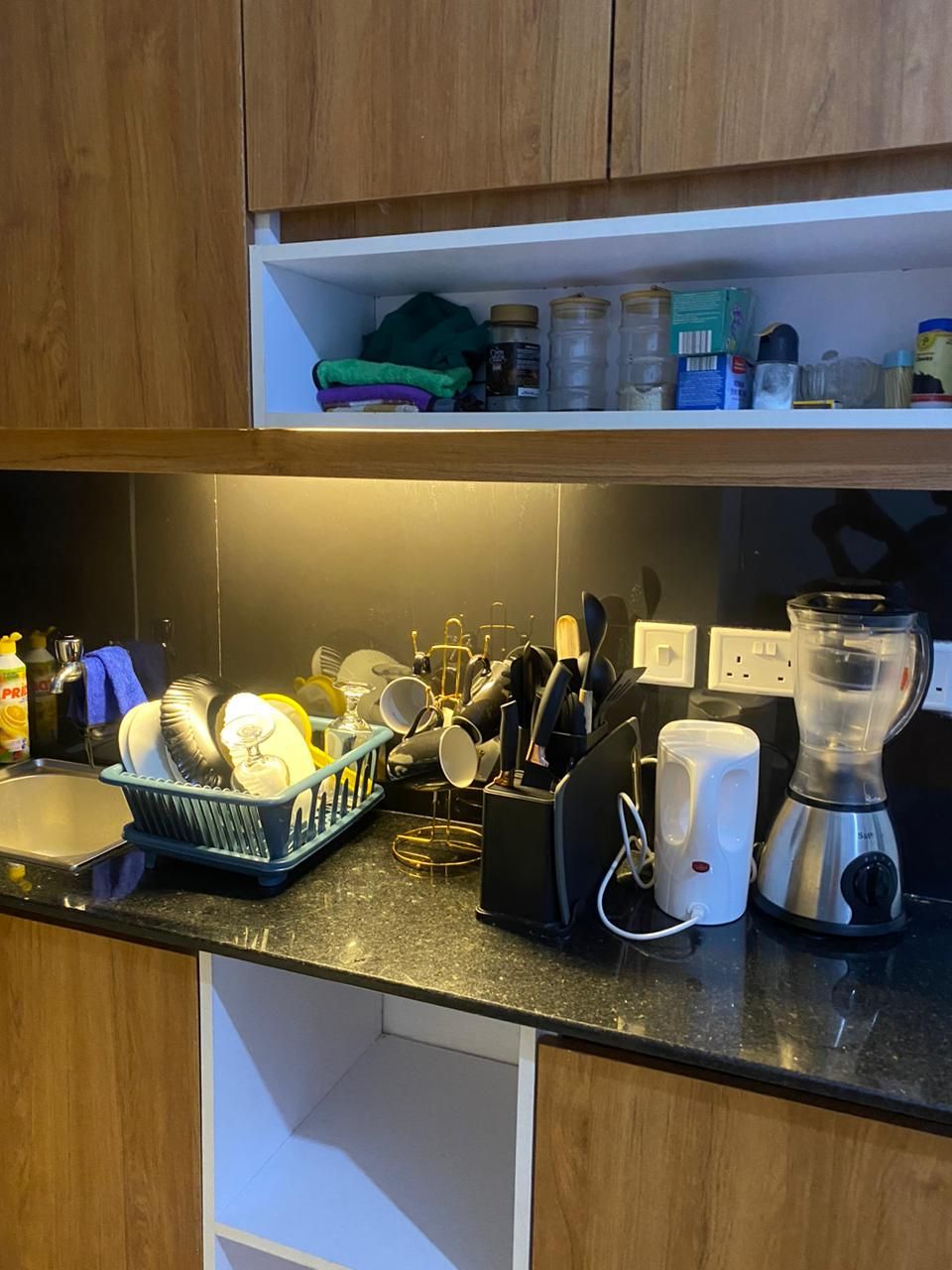 A kitchen with a dish rack, a blender, and various kitchen utensils.
