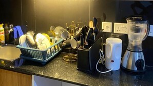 A kitchen with a dish rack, a blender, and various kitchen utensils.