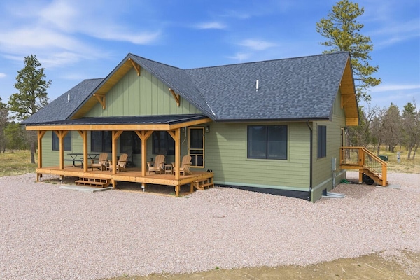 Arrive at a charming green cabin with a welcoming covered porch, blending rustic design with modern comfort.