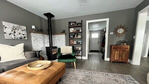 Een woonkamer met een open haard, een bank, een salontafel en een tapijtendecor.