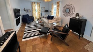 Een woonkamer met een piano, banken, een salontafel en een decoratieve spiegel.