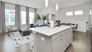 Une cuisine moderne avec un îlot central, un coin repas avec un canapé et un salon avec une table basse.