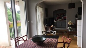 Ein Essbereich mit Tisch, Stühlen und einer Schüssel. Im Hintergrund ist eine Küche zu sehen.