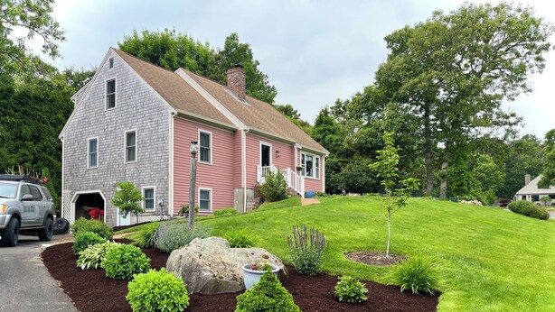 Ein zweistöckiges Haus mit einem gepflegten Rasen und Garten.