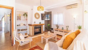 A living room with a fireplace, a sofa, a coffee table, and a TV. - Villa María Sayalonga by Ruralidays (Málaga)