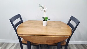 Pyöreä puinen pöytä, jonka päällä on valkoinen kukkaruukku, ja pöydän ympärillä on neljä mustaa tuolia.