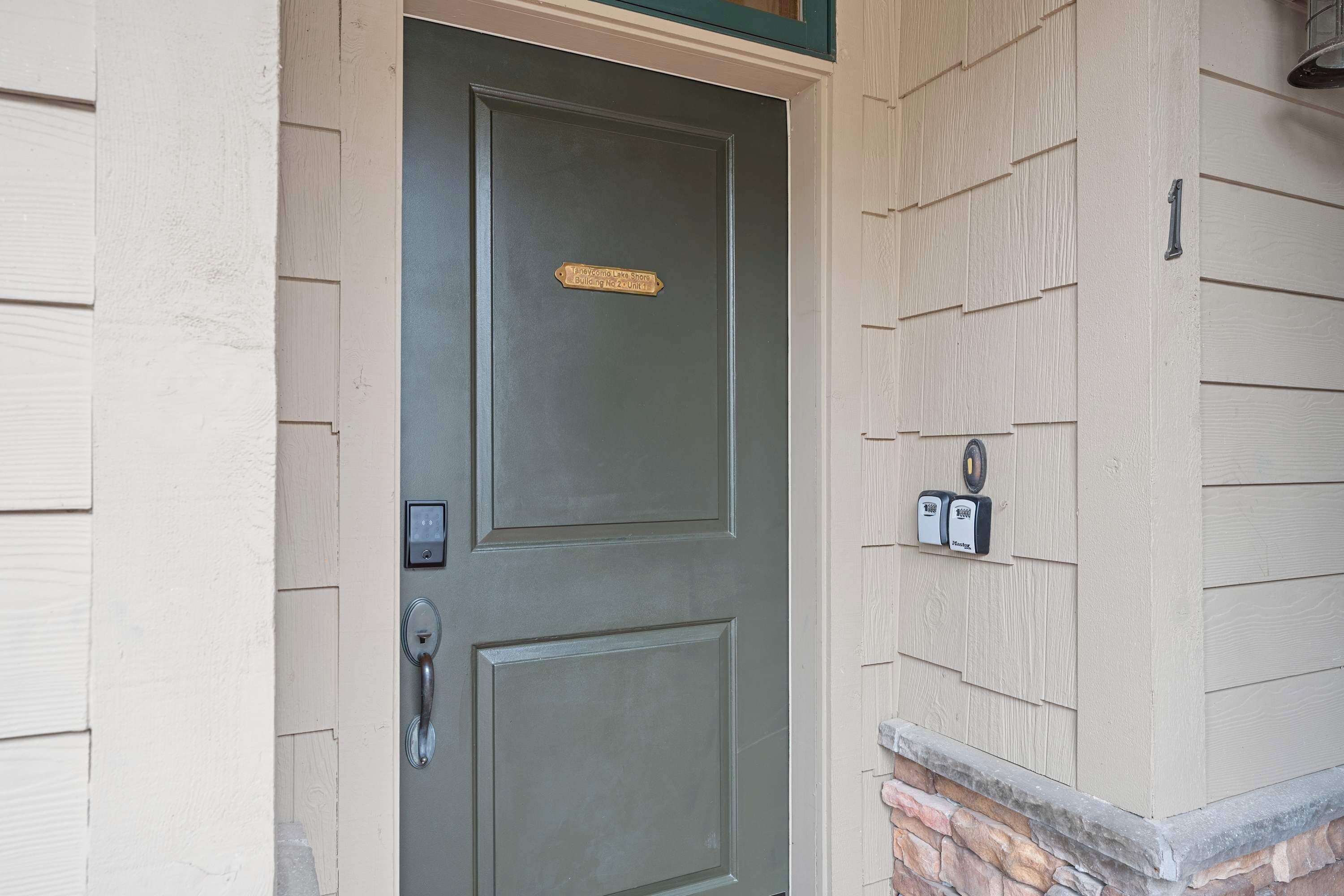 Une porte avec une plaque, une boîte aux lettres et un socle en pierre.