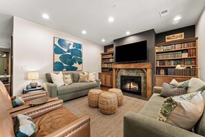 A living room with a fireplace, a television, and a bookshelf. - Newly Renovated! Walk-In Condo on Lake Taneycomo! (Branson)