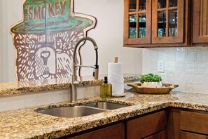 A kitchen with a granite countertop, stainless steel sink, and wooden cabinets. - Newly Renovated! Walk-In Condo on Lake Taneycomo! (Branson)