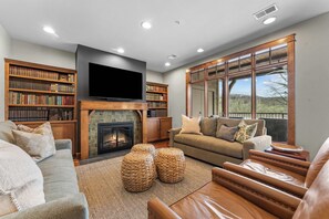 A living room with a fireplace, bookshelves, a television, and a sofa. - Newly Renovated! Walk-In Condo on Lake Taneycomo! (Branson)