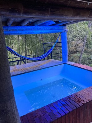 Ein Whirlpool mit Holzterrasse und einer Hängematte.