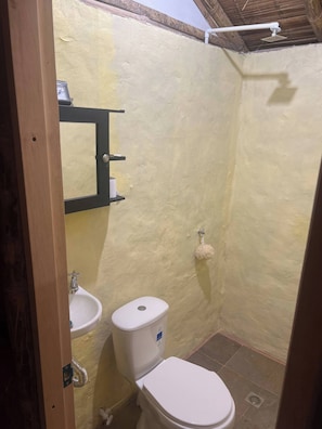 Ein kleines, kompaktes Badezimmer mit Toilette, Waschbecken und Dusche.