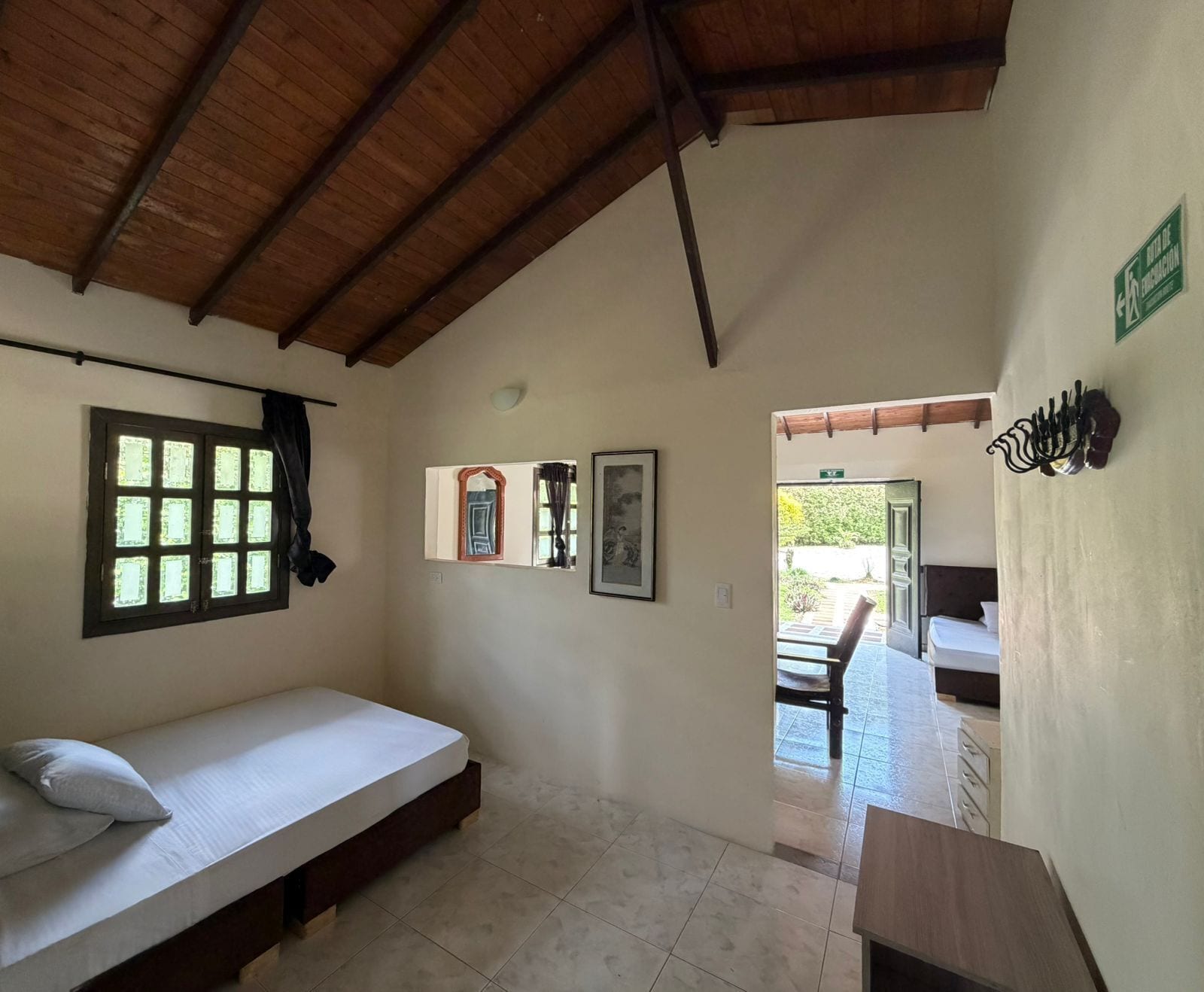 A room with a bed, a window, a door leading outside, and a small table.