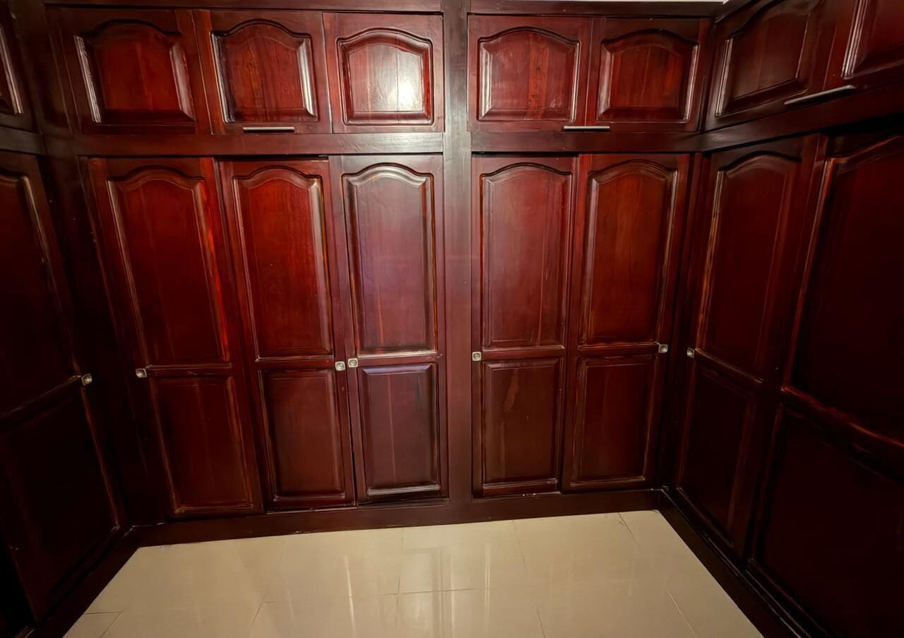 Una habitación con un armario grande, piso de baldosas y una pared lisa.