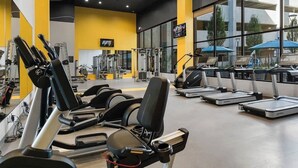 Un gimnasio con cintas de correr, máquinas de pesas y un amplio ventanal.