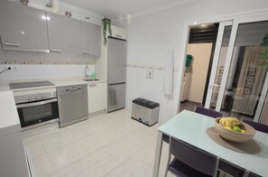A modern kitchen with stainless steel appliances, a dishwasher, and a dining area with a table and chairs. - Los Alisios House, Lanzarote (Costa Teguise)