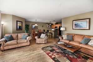 A living room with two sofas, a coffee table, and a dining area with chairs and a table. - Marina Cay Condo Retreat (Bigfork)