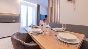 A dining area with a wooden table set for four, a sofa, and a decorative wall piece.