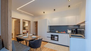 A modern kitchen with white cabinets, a dining area with a table set for two, and a wooden floor.