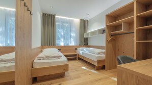 A room with two wooden beds, a desk, and a wardrobe.