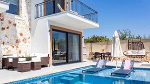 A swimming pool with lounge chairs, a dining area with wicker furniture, and a balcony with a railing. - Holiday villa in Kaş / Antalya, on the most turquoise sea of the Mediterranean. (Antalya)