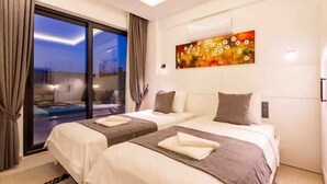 A hotel room with two beds, a large window with curtains, a painting on the wall, and a ceiling light. - Holiday villa in Kaş / Antalya, on the most turquoise sea of the Mediterranean. (Antalya)