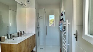 Un baño moderno con tocador de doble lavabo, cabina de ducha de vidrio y perchero para toallas.