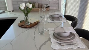 A kitchen island with a marble countertop, white cabinets, and a window with curtains. - FIFA Fans! Brand-NEW 1 Bedroom, 1 Bath Apartment  (San Jose)