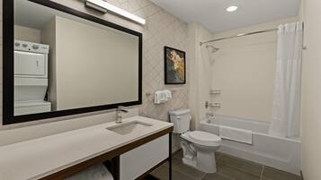 Un baño moderno con un espejo grande, un lavabo, un inodoro y una bañera.