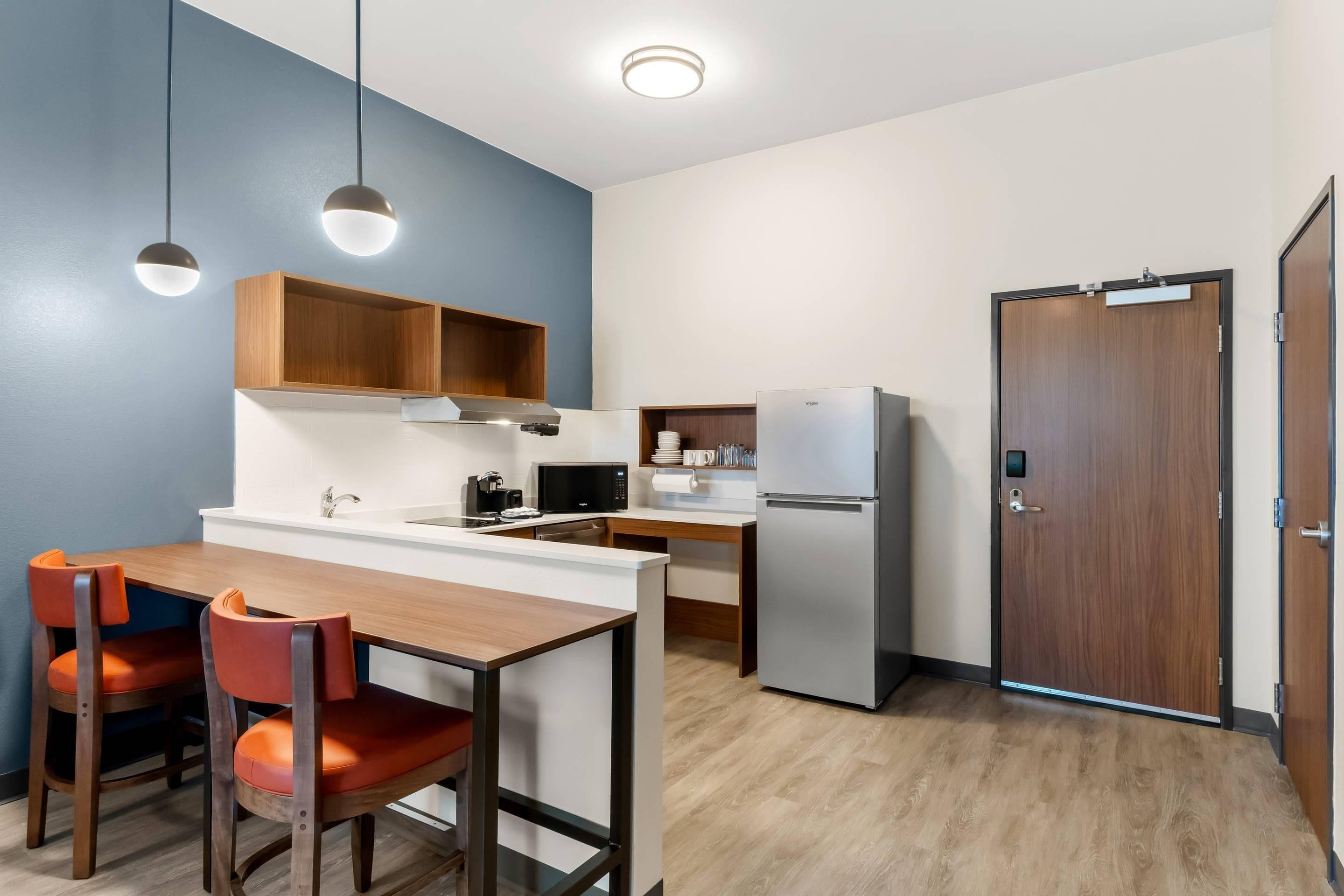 Una cocina compacta con comedor, microondas, refrigerador y una puerta de madera.